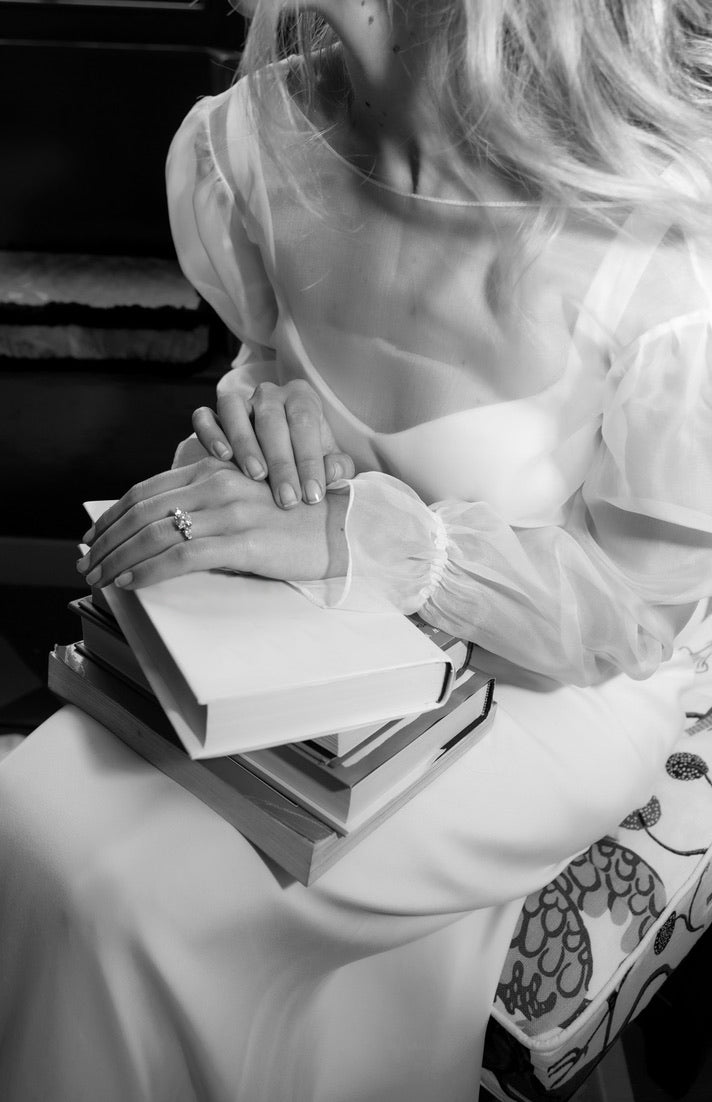 Bride sitting in her wedding dress with bespoke diamond trilogy engagement ring from London designer Antonia Guise