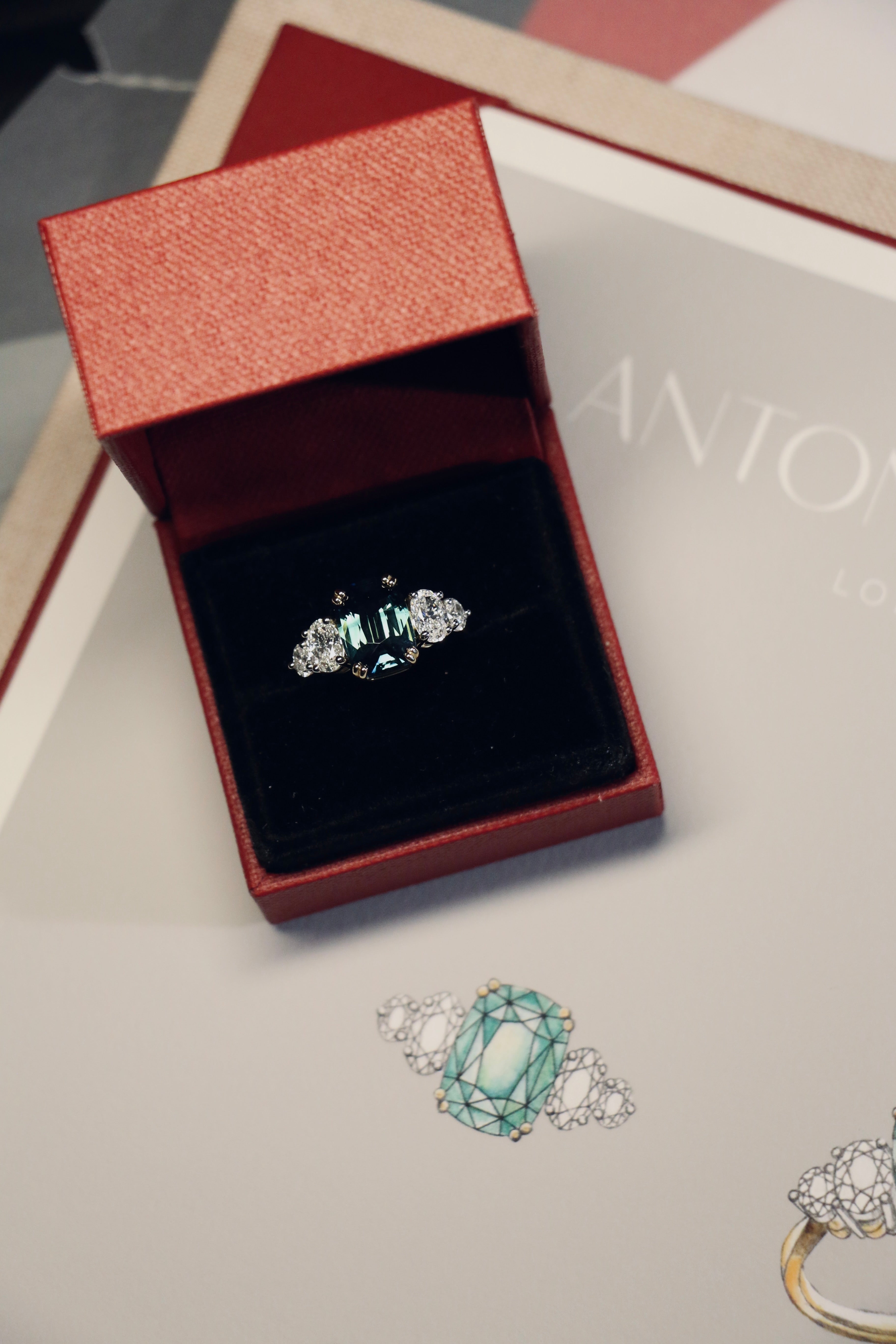 Designed by London based engagement ring designer Antonia Guise. A unique unheated 6.06ct teal sapphire engagement ring in its box alongside hand drawn original designs for the ring.