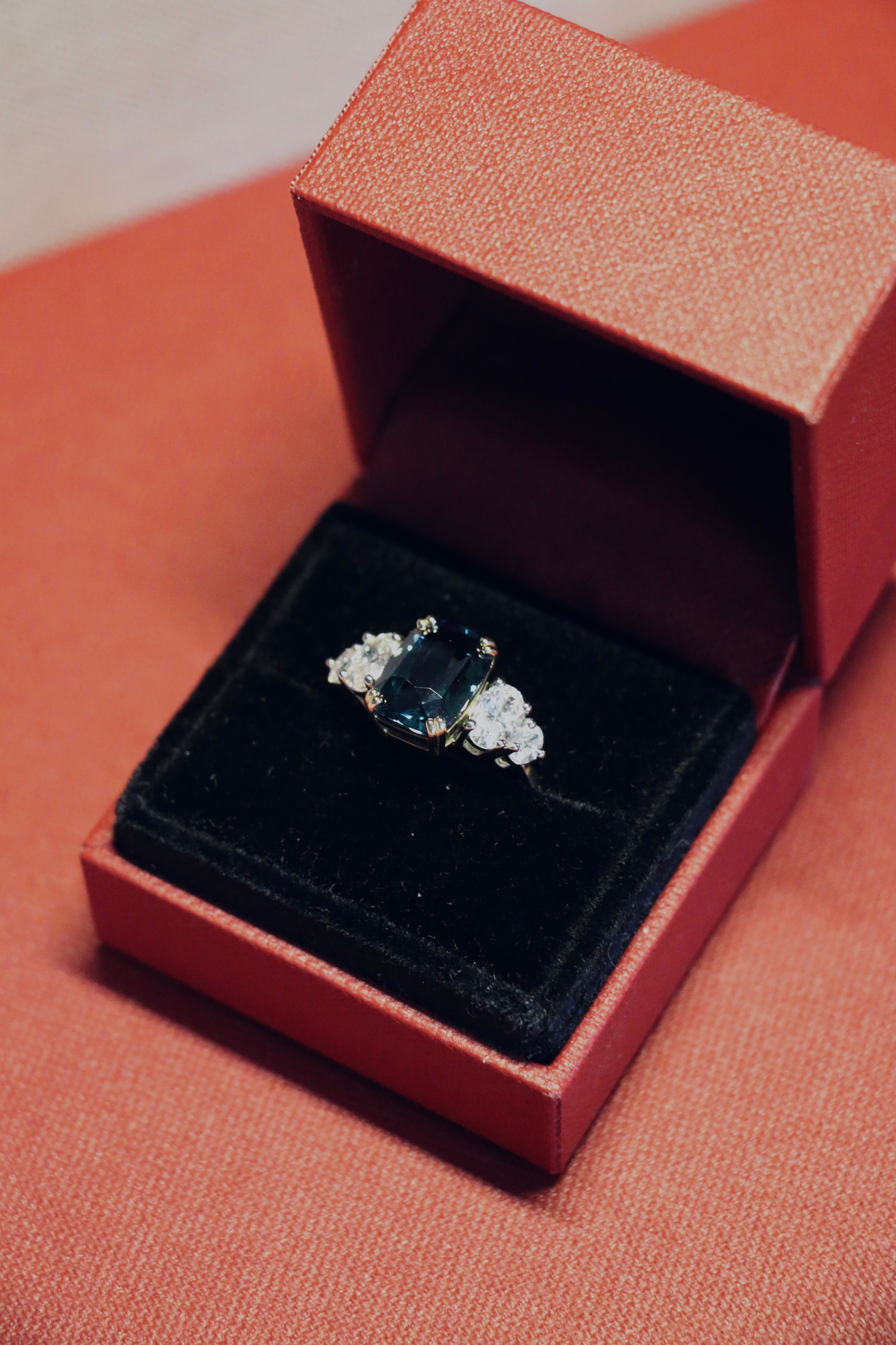 A teal sapphire, one of a kind, engagement ring, designed by jewellery designer Antonia Guise in it's ring box.